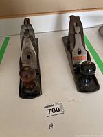 Photo of two wood hand planes side by side, Millers Falls on the left and Stanley on the right, showing front knobs and rear handles.