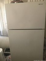 Front view of the white ice box refrigerator with top freezer and lower refrigerator door, closed.