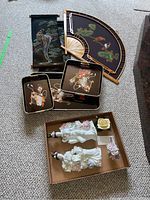 Full view of the velvet scrolls, painted fan, trays, figurines, and floral baskets laid out on carpet.