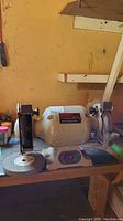 Front view of the bench grinder showing grinding wheel on left side, wire brush wheel on right side, and device bolted to wooden bench.