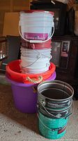 Full view of stacked assortment of buckets and pails in garage
