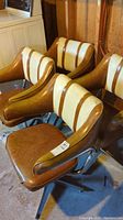 Four vintage swivel chairs with brown and cream vinyl cushions and metal swivel bases positioned in a basement area with visible wear on vinyl upholstery.