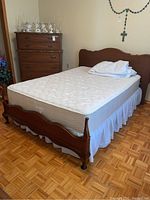 Photo of the full double wooden bed setup with mattress cover and footboard visible