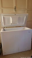 Front view of Kenmore white chest freezer with lid open inside a garage, showing interior and lid design.