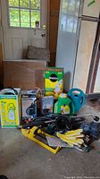Photo of all gardening supplies including boxed sprayer, pump, Miracle-Gro fertilizer, watering can, gloves, sprinklers, and solar lights.
