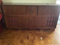 Full view of the Koronette stereo console showing solid wood cabinet with two speaker compartments with red cloth covers and central control panel section.
