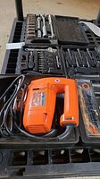Photo showing Orange Black & Decker variable speed jigsaw laying inside carrying case along with portions of socket set visible.