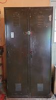 Front view of dark brown metal locker with two doors showing corrosion and paint wear