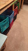 Side view showing various colored milk crates stacked on a floor under a bench.