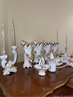 Full view of the white porcelain set showing the candle holders, vases, basket, trinket boxes and chicken figurine arranged on a wooden table