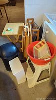 Photo showing wooden TV tables, shoe rack, plastic and metal step stools, trash bins, storage totes all grouped together.
