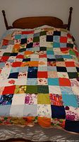 Full view of the handmade quilt spread on a double bed showing its colorful patchwork pattern