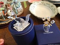 Two Swarovski figurines displayed on blue boxes, wolf and flower vase.