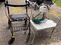 Four-wheeled Dolomite walker with seat and basket next to a white plastic shower seat with backrest and armrests, outdoors on pavement.