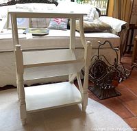Photo of white painted wooden book shelf with three shelves; middle shelf is slanted, designed for books.