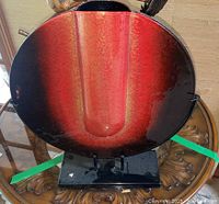 Front view of the red and black glass sculpture on metal base showing its oval shape and color gradient.