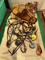 Image showing amber-colored art glass swan figurine holding several pieces of glass bead costume jewelry such as necklaces with various pendants and cords.