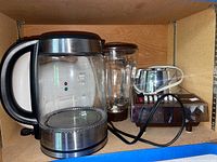 Photo of electric kettle, blender, and sandwich maker on wooden shelving showing appliance details and condition