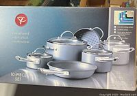 Front of box showing 10-piece anodized non-stick cookware set including pots, pans, lids with stainless handles