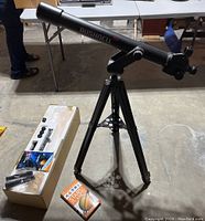 Bushnell 450 telescope on tripod with original box and the Smithsonian Nature Guide - Stars and Planets book on the ground.