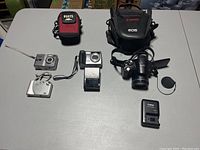 Overview photo of all cameras, chargers, and cases included in the lot arranged on tabletop.