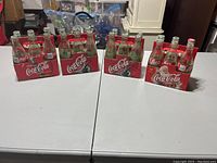 Four cardboard carriers holding 24 empty vintage glass soda bottles including Coca-Cola, Sprite, Crush, and Hires with classic labels.