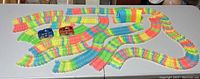 Overview of the Magic Tracks toy set showing the assembled multi-colored flexible track and two small toy cars on the track.