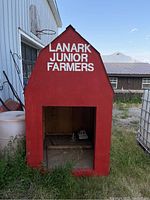 Front view of miniature red barn structure with open large doorway and text 'LANARK JUNIOR FARMERS' in white.