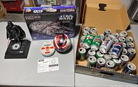 Darth Vader animated coin bank, Puzz 3D Millennium Falcon puzzle box, Catch Phrase game, bouncy ball, and box of empty Star Wars themed pop cans.
