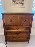 Front view of the wooden dresser showing the cabinet doors, drawers, decorative handles, and detailed wood grain.