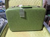 Green large vintage suitcase exterior closed, showing textured hard shell and handle