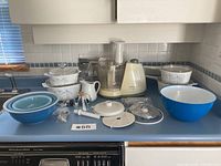 Full overview of all items on kitchen counter including Corningware dishes, Black and Decker food processor, Pyrex bowls, and white creamer.