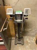 Front view of Craftsman 1/3 HP bench grinder mounted on pedestal stand, showing both grinding wheels, enclosures, and lamps.