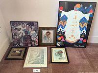 Overview of six framed art pieces arranged on floor against wall including Expo 86 Lover's Leap poster.