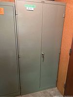Full view of tall gray metal cabinet with a locking door and label #36 on front.