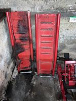 Photo showing two red metal motorcycle ramps with ribbed surfaces used for loading motorcycles onto the trolley jack.