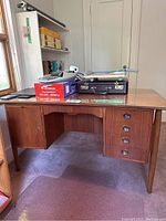 Full frontal view of the teak desk showing glass top, left cabinet and right drawers