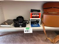 Shelf overview showing Pentax Spotmatic camera, Olympus Trip 35 in box, brown camera bag