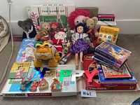 Full lot shown including plush dolls, books, board games, VHS tapes, holiday decorations.