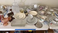 Table display of crystal ice bucket, various ceramic plates and bowls, glassware including dessert bowls and shot glasses, and decorative items arranged