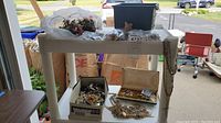 Full view of jewelry pieces arranged on a white display stand with black jewelry box and small cases containing necklaces and earrings