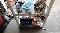 Wide shot showing multiple jewelry pieces on white shelving including necklaces, bracelets, and small boxes.
