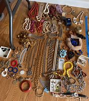 Full overview of costume jewelry including necklaces, bracelets, and rings spread out on floor