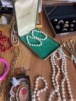Assorted necklaces, bracelets and brooches laid out on table
