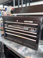 Front view of closed black Craftsman metal tool box showing brand logo and keyhole lock.