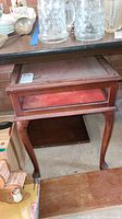 Full view of wooden display table showing the top glass display area, curved cabriole legs, and claw feet.