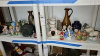 Shelf with assorted vintage figurines, ceramic vases, ginger jar, and decorative items