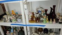 Wide shot of shelf with various figurines, vases, candlesticks, and coffee maker