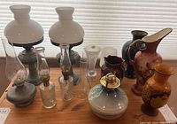 Photo showing entire collection of oil lamps and vases with different materials and sizes on a wooden surface