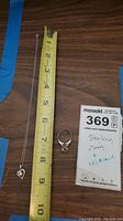 Necklace next to tape measure showing approximate length and ring next to note card with seller description.